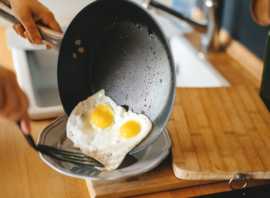 Woman plating fried eggs sunny side up - endometriosis diet