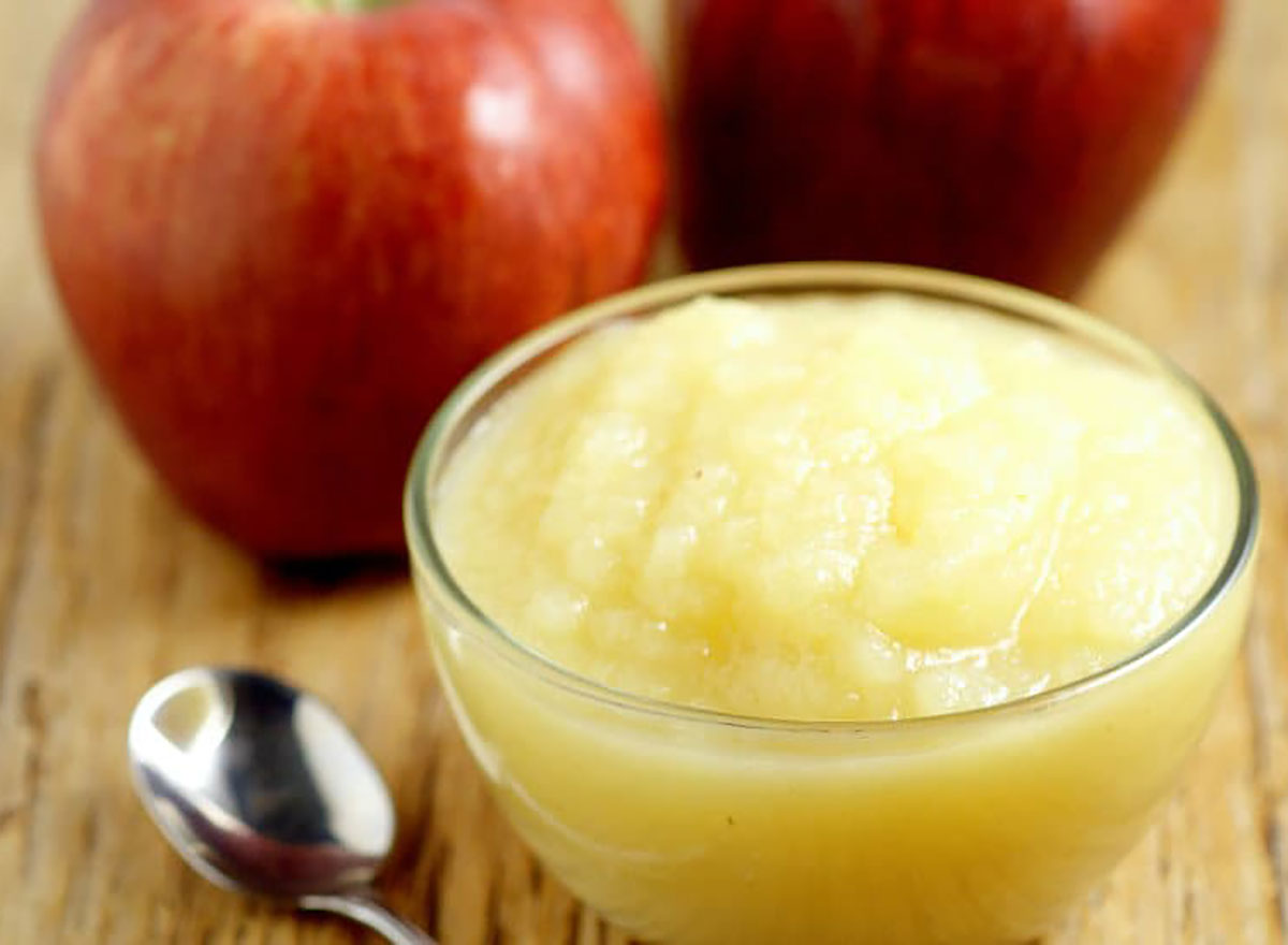 homemade applesauce in glass bowl with spoon and whole apples