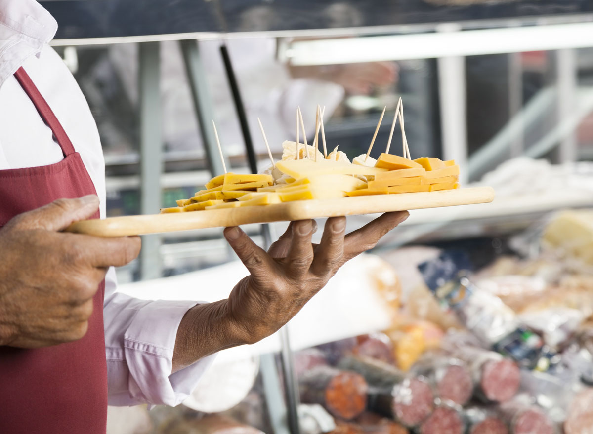 Man holding cheese board of free samples at grocery store