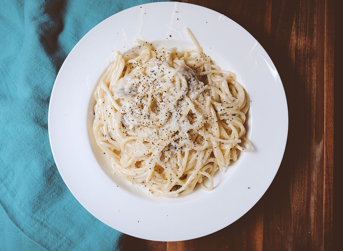 bowl of alfredo pasta with cheese and pepper