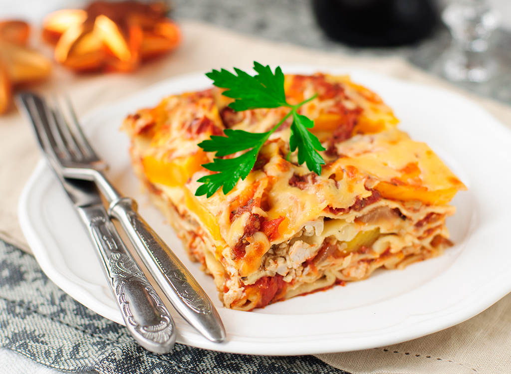 serving of lasagna on plate with fork and knife
