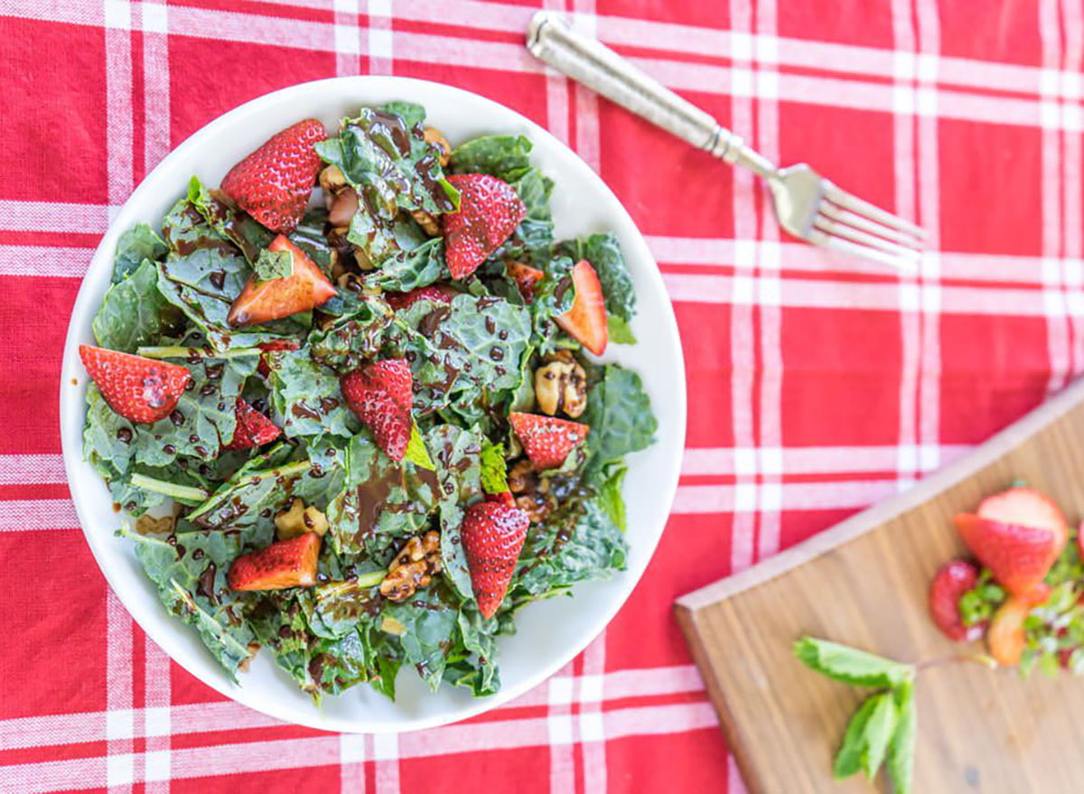 strawberry kale salad on red checkered tablecloth