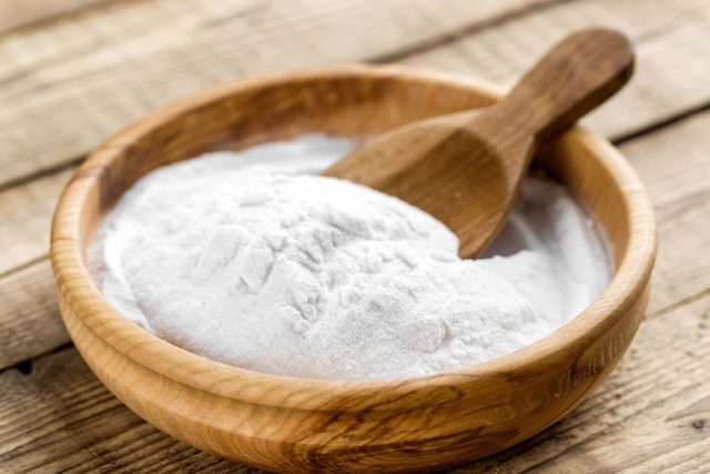 Baking soda in wooden bowl with wooden spoon