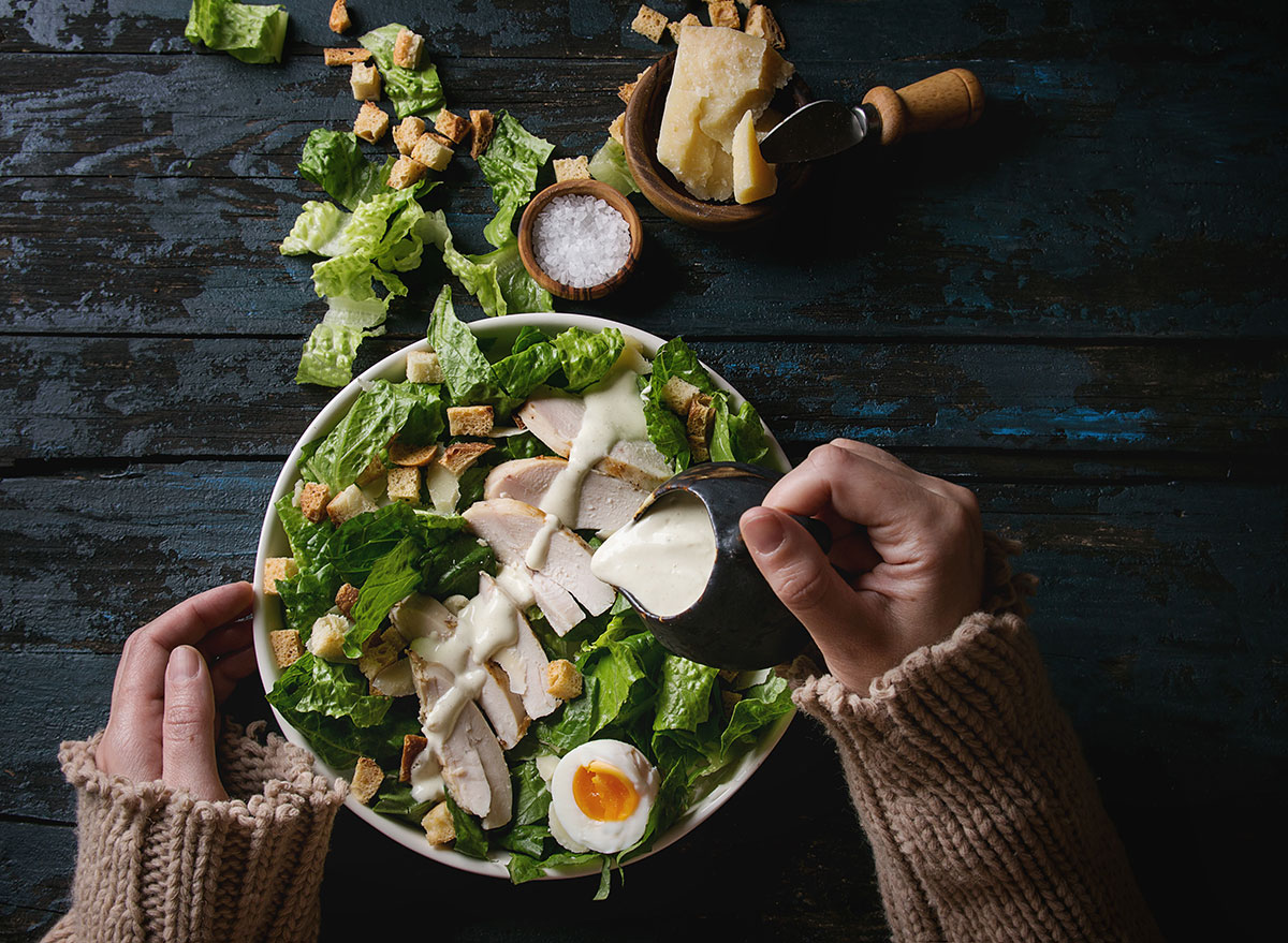 Caesar salad with dressing being poured