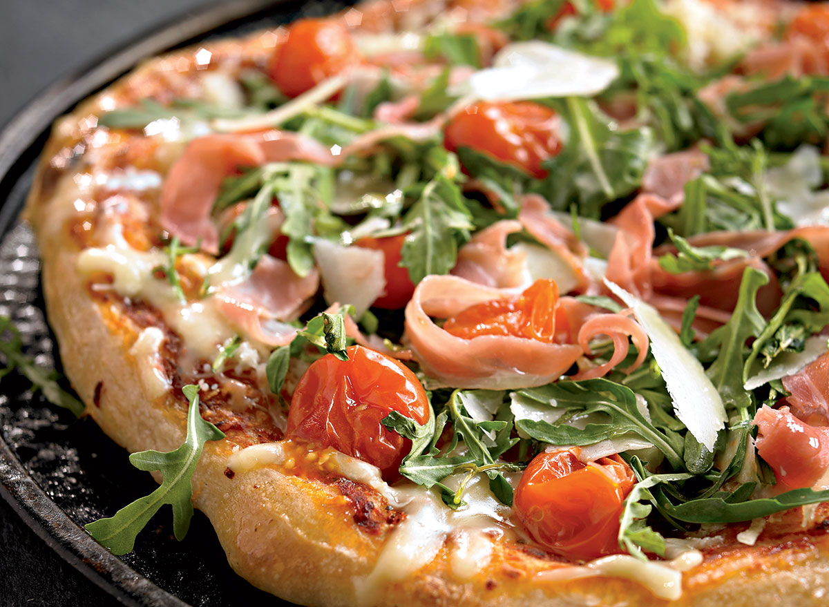 Healthy pizza with arugula, cherry tomatoes and prosciutto