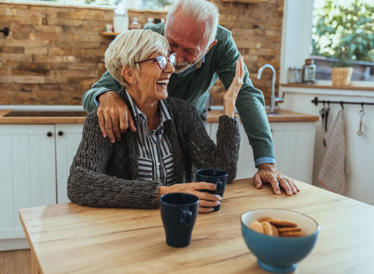 older mature happy couple at table eating drinking