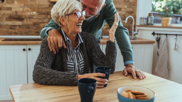 older mature happy couple at table eating drinking
