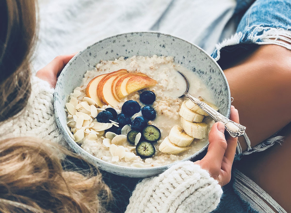 Woman eating oatmeal breakfast fresh fruit