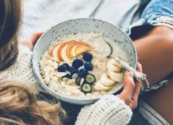 Woman eating oatmeal breakfast fresh fruit