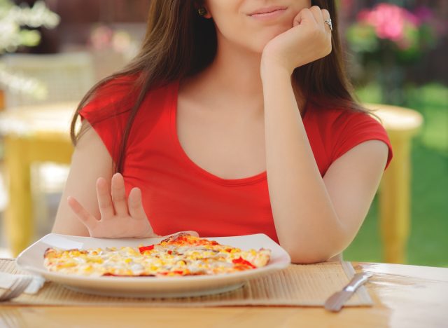 Woman pushing a plate of pizza to skip a meal