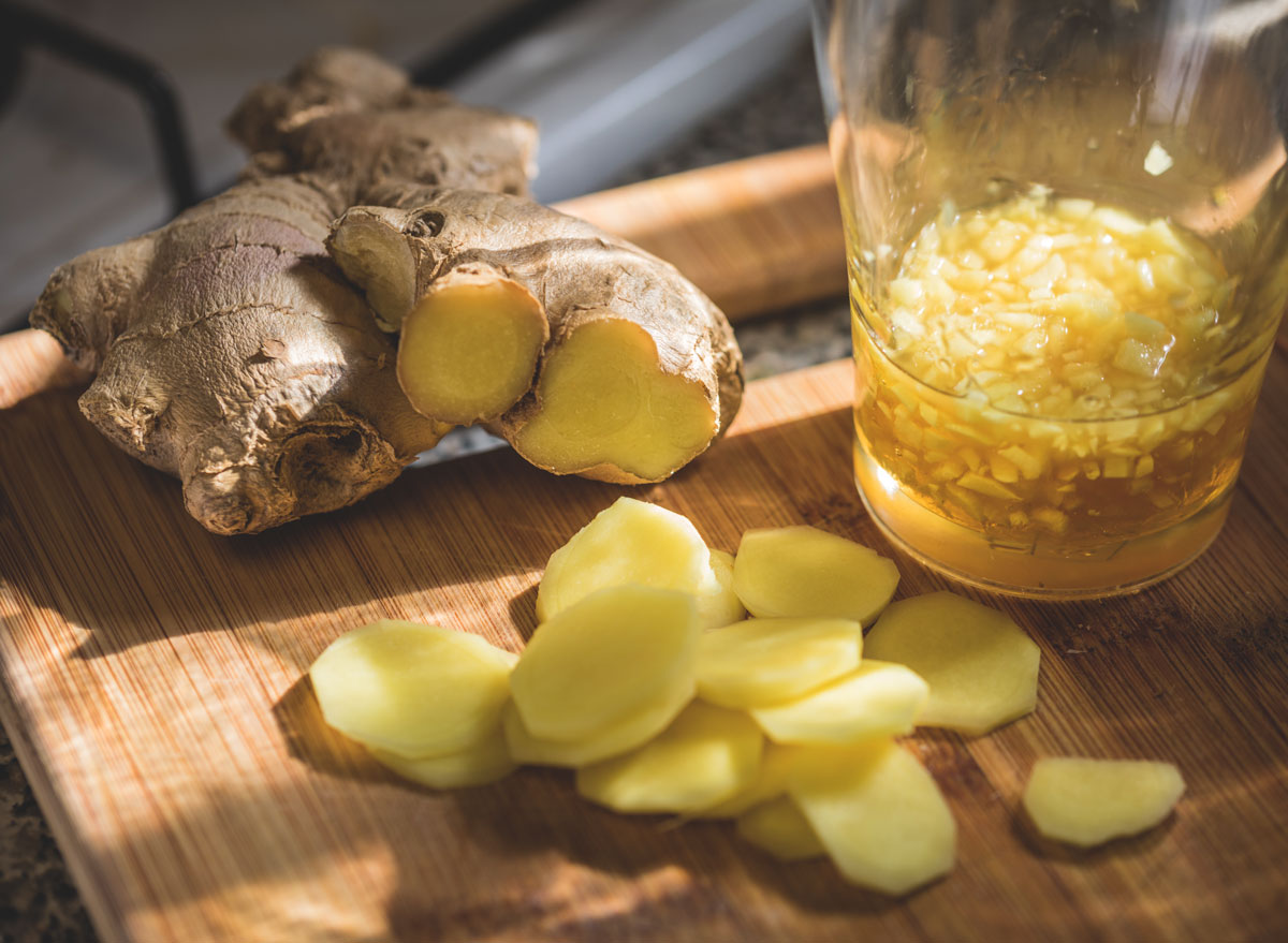 Sliced ginger and ginger root on wooden cutting board