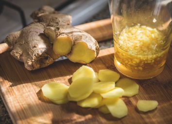 Sliced ginger and ginger root on wooden cutting board