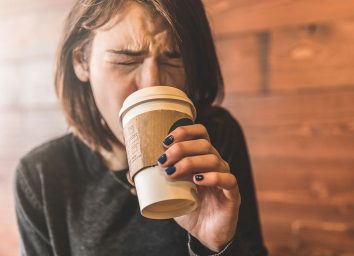 Girl cringing at hot coffee cups