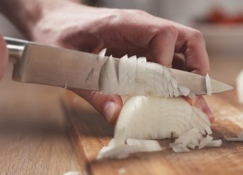 person-chopping-onion-on-cutting-board