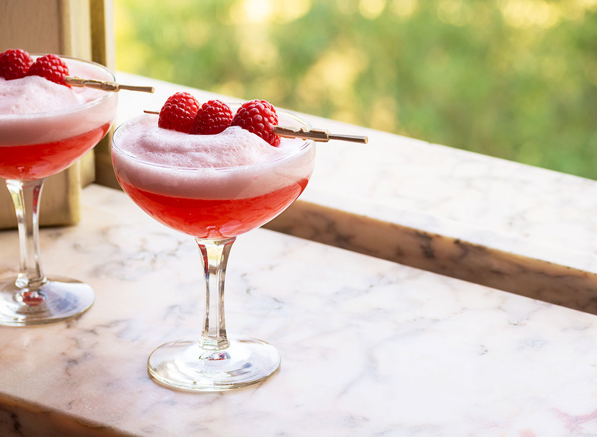 clover club cocktail on window sill with raspberry garnish