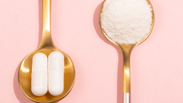 collagen pills and powder on gold spoons pink background