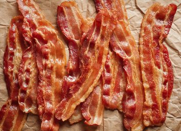 strips of cooked bacon lying on brown parchment paper