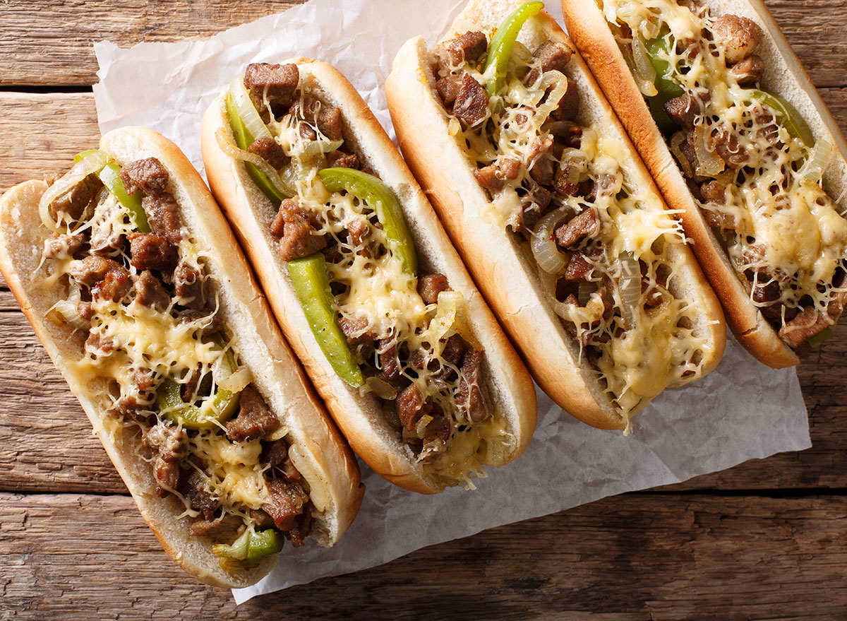 four philly cheesesteaks with cheese and peppers