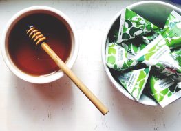 Honey in bowl next to bowl of sugar packets