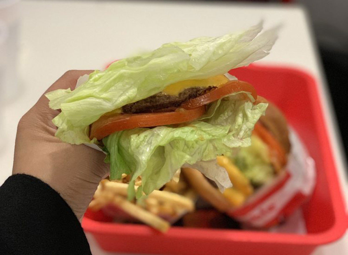 In-n-out regular cheeseburger protein style held over tray