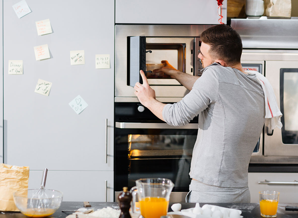 man on phone distracted cooking with microwave