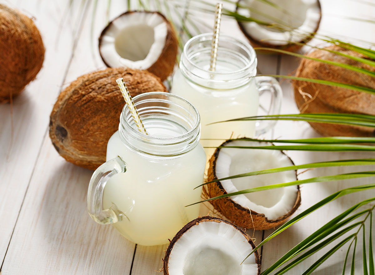 mason jar mugs filled with coconut water around coconuts