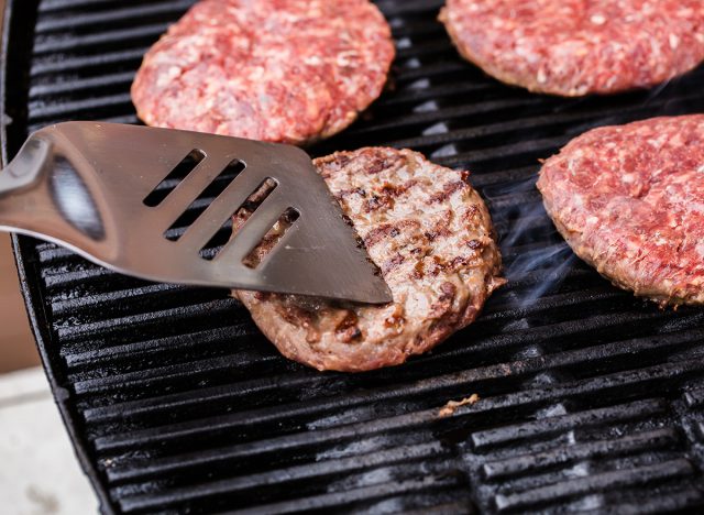 spatula pressing down on a beef patty that's on a grill