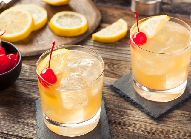 whiskey sour cocktails in glass with cherry lemon garnish