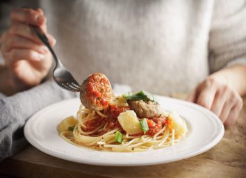 Woman eating pasta meatballs for dinner