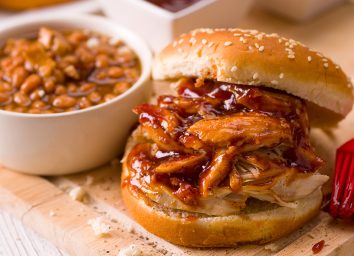 BBQ pork sandwich with a cup of beans