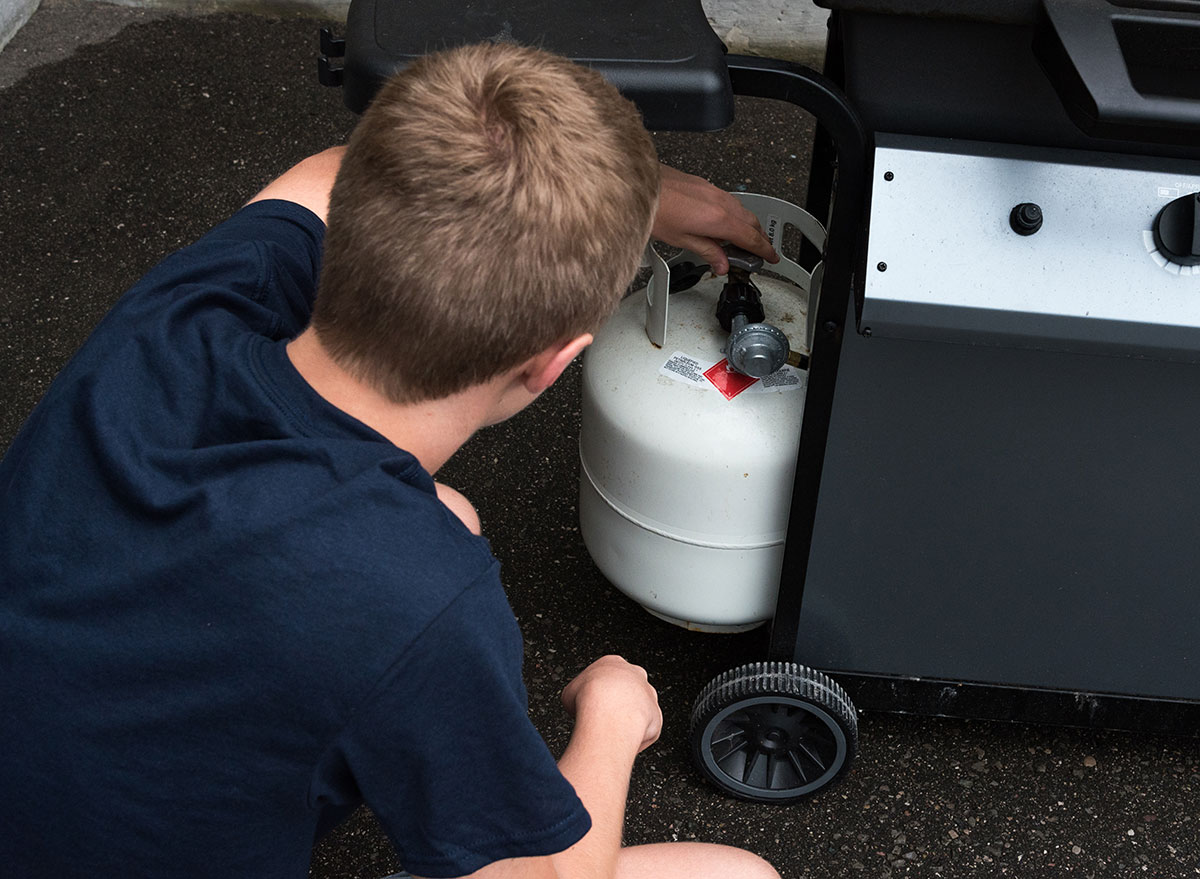 boy touching propane tank for grill