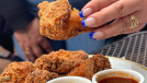 a hand holding fried chicken from buttermilk and bourbon.