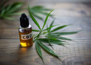 cbd oil bottle next to marijuana leaf