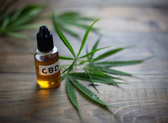 cbd oil bottle next to marijuana leaf