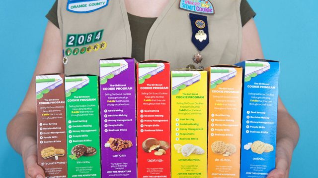 girl scout holding boxes of cookies