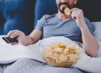 man watching tv and eating chips