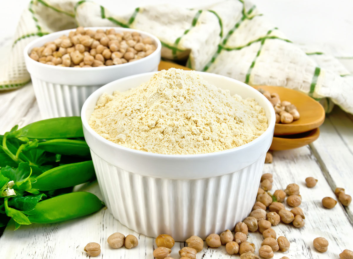 Pea protein powder in white ramekin next to whole pea pod