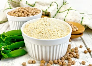 Vegan pea protein powder in white ramekin next to whole pea pod