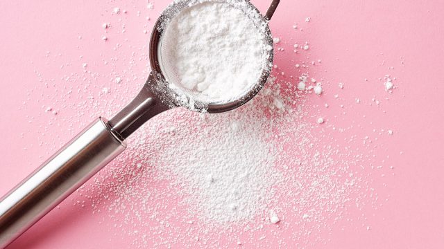 powdered sugar in a portable sifter on a pink background
