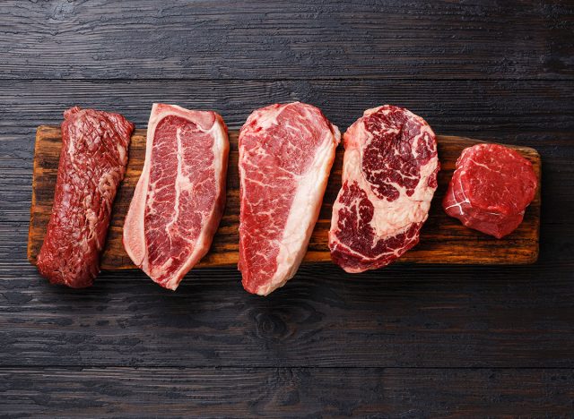 slabs of different cuts of red meat on wooden cutting board