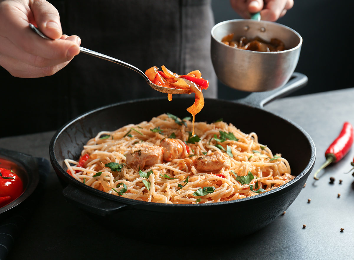 adding toppings to pasta