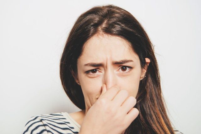 Woman holding nose because of bad smell