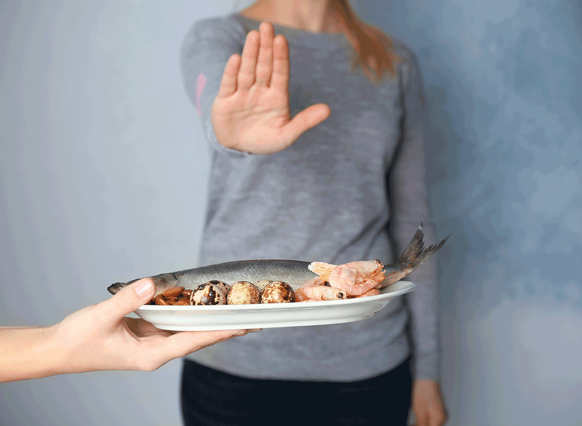 woman refusing plate of fish