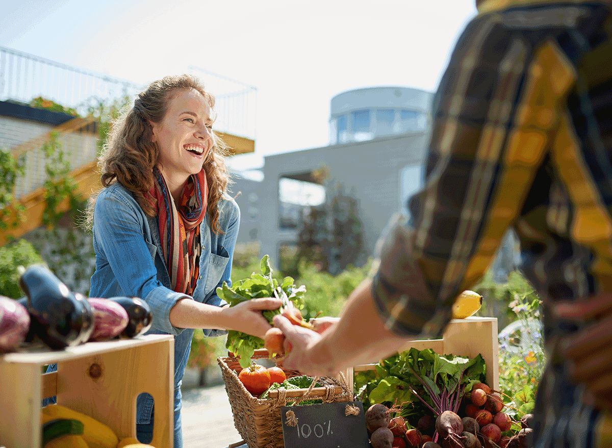 woman smiling buying sustainable food from stand