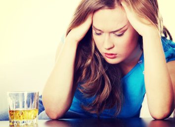 woman holding head from alcohol - how does alcohol affect the brain