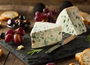 blue cheese on cheese board with crostinis and purple grapes