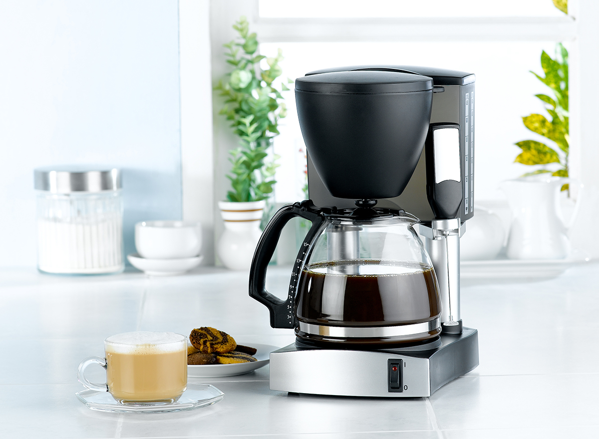 coffee maker sits next to a latte and cookies