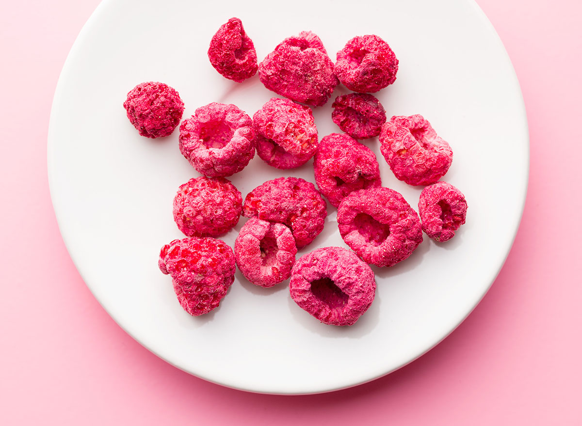 freeze dried raspberries on white plate pink background