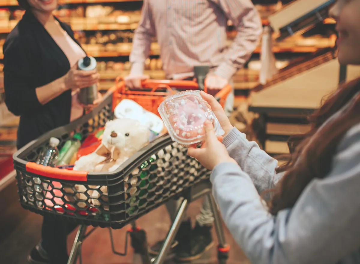 Parents grocery shopping with kid who holds doughnut