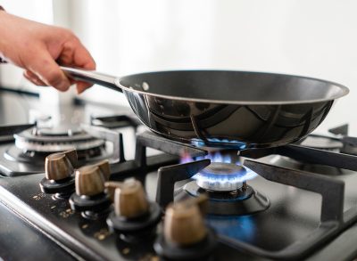 person holding skillet on stovetop